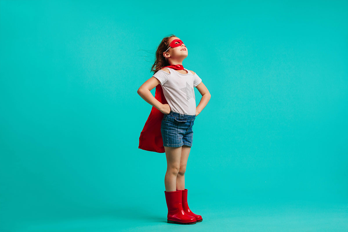 child posing as superhero
