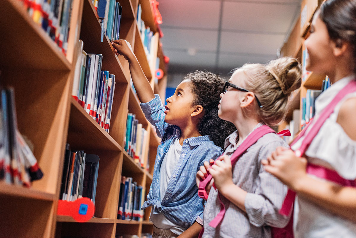children picking out books from library shelves